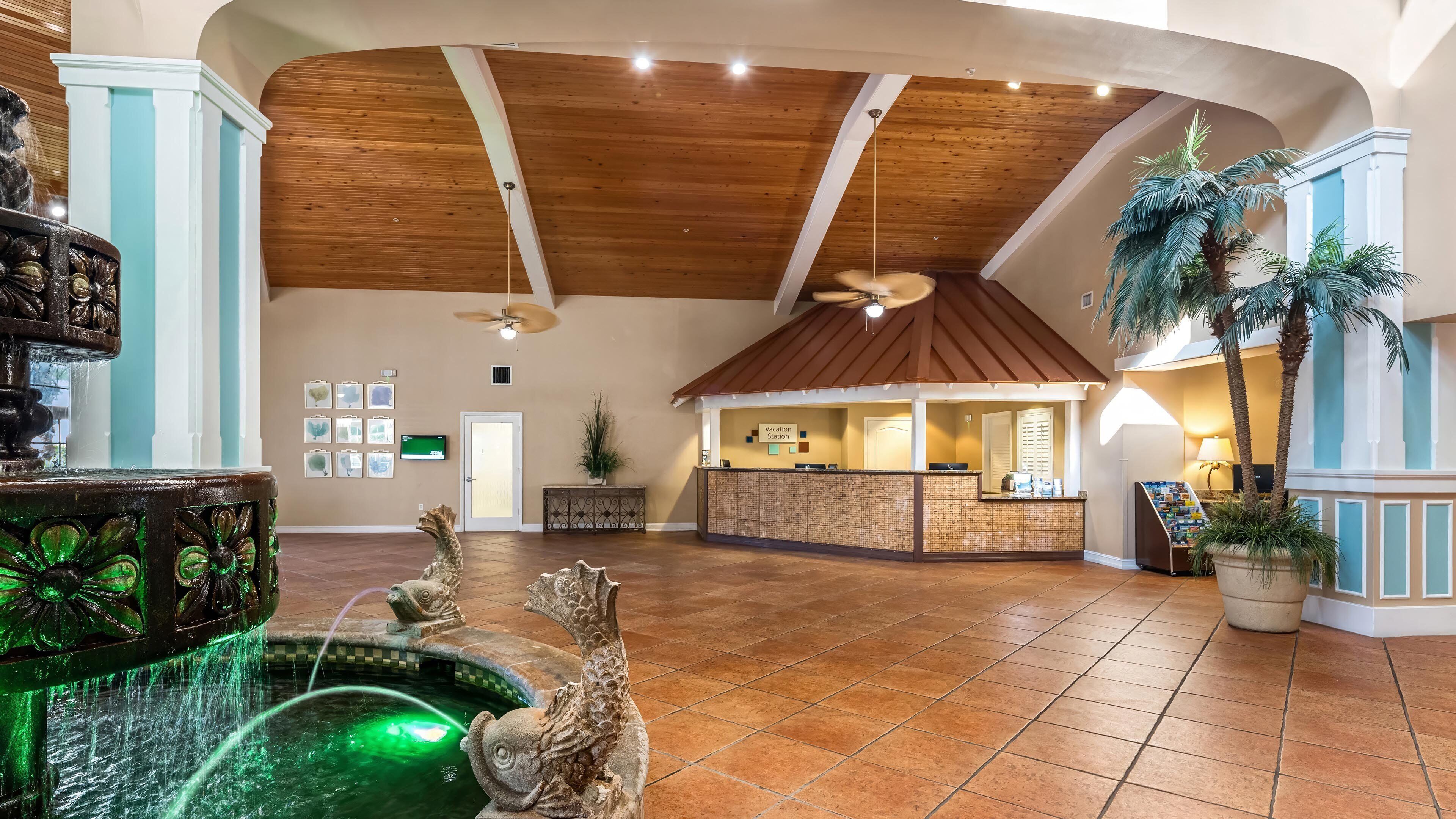 A spacious lobby with a reception desk, a fountain, and a ceiling fan.