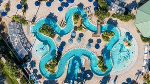 Vista aérea de una zona de piscina con varias piscinas, tumbonas y sombrillas.