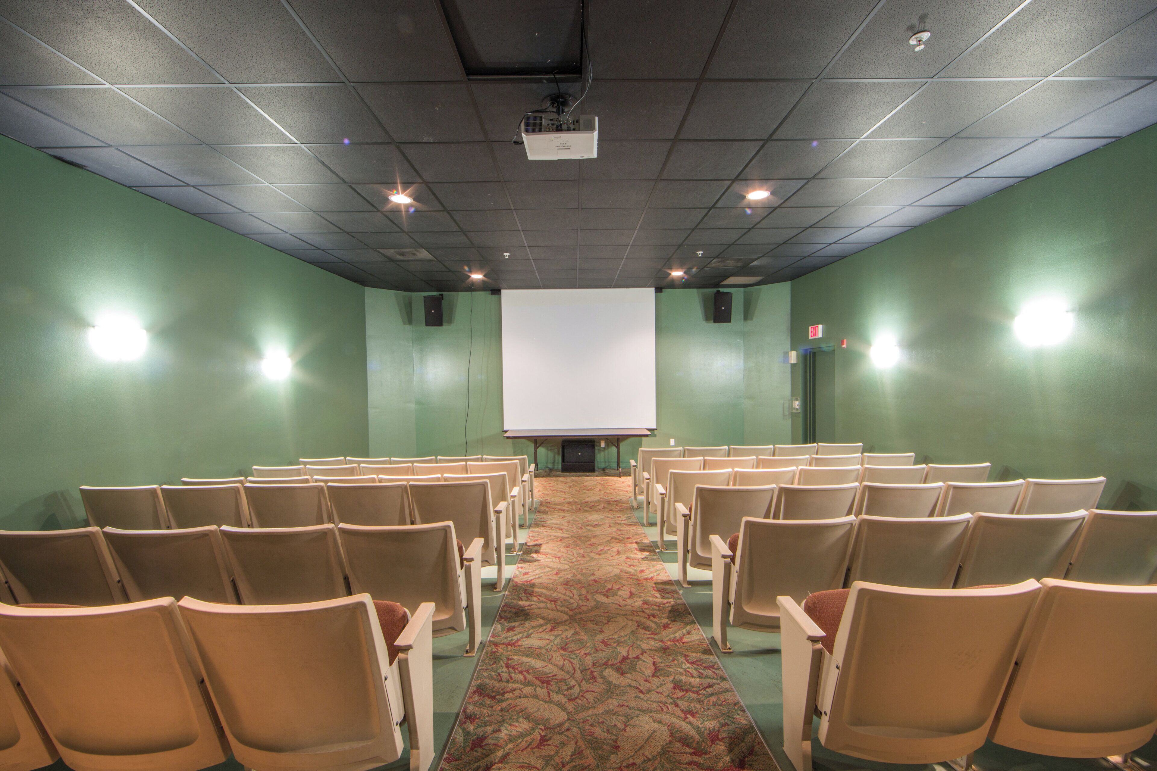A conference room with rows of chairs facing a projection screen.