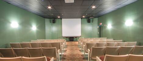 A conference room with rows of chairs facing a projection screen.