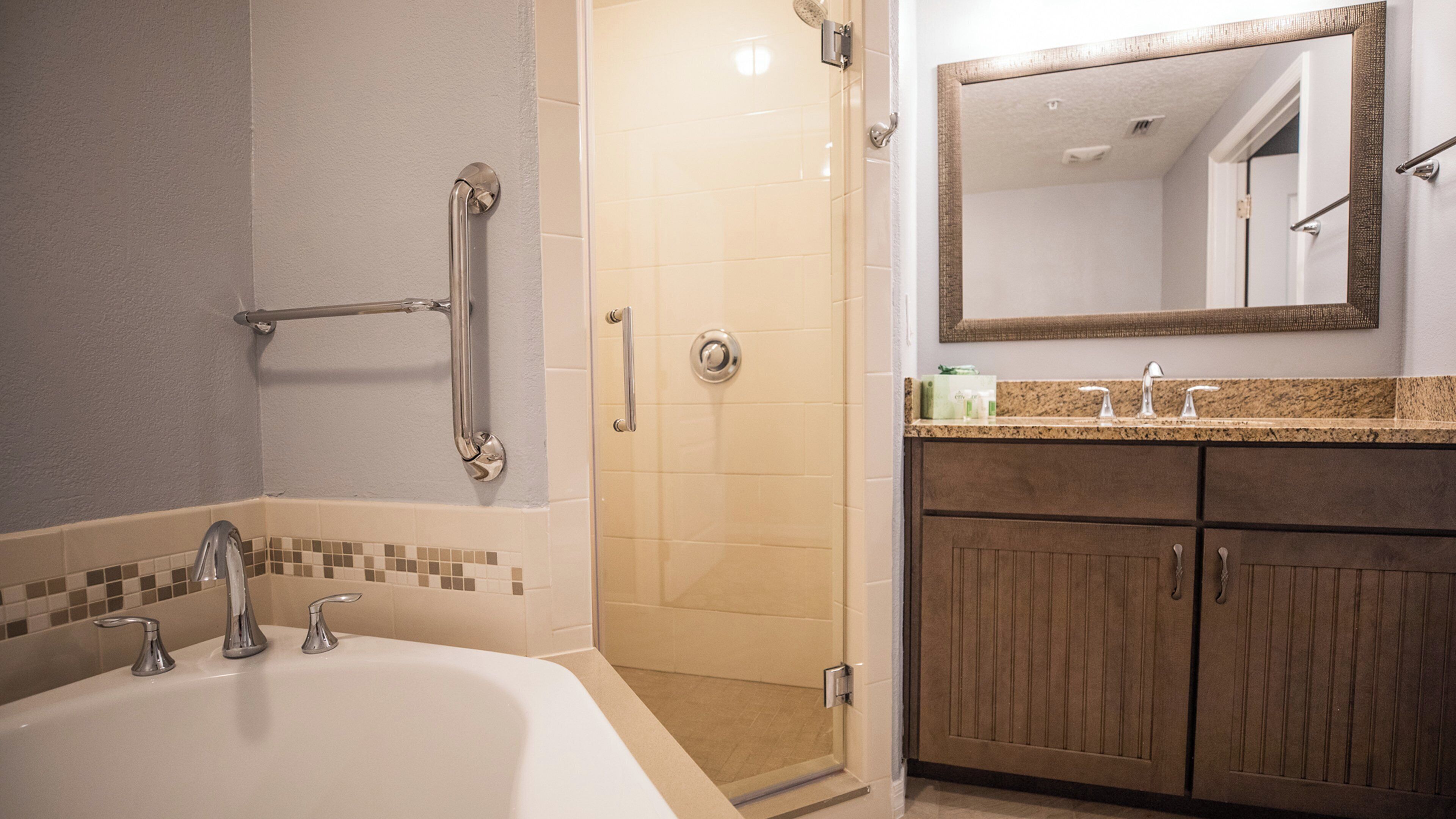 A bathroom with a bathtub, a shower, and a vanity with a mirror.