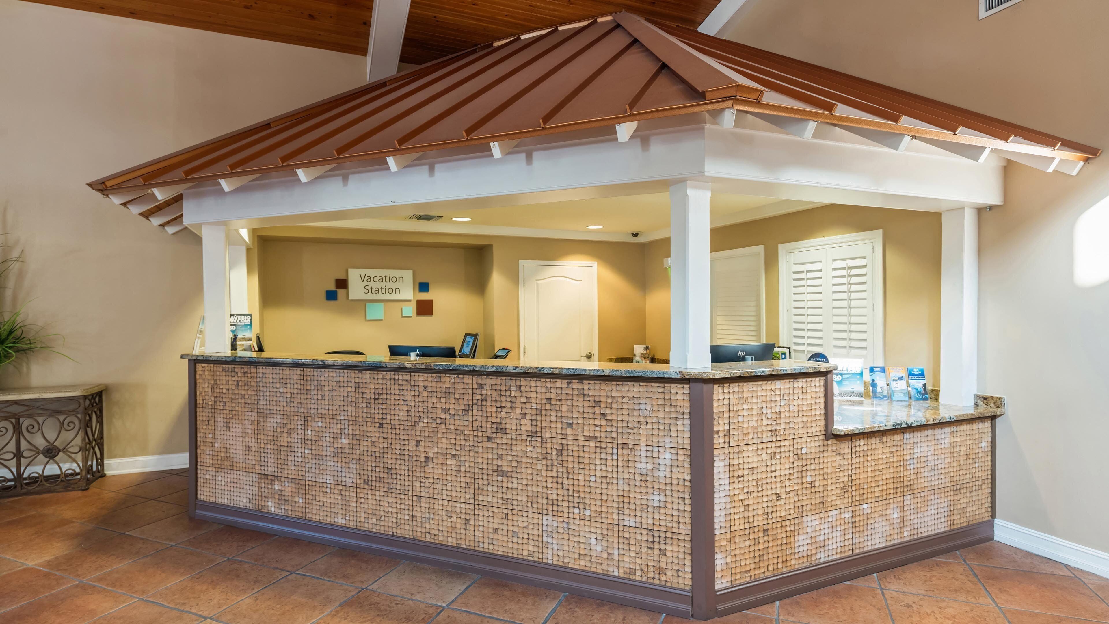 A reception area with a tiled counter, a sign reading 'Vacation Station,' and a door in the background.