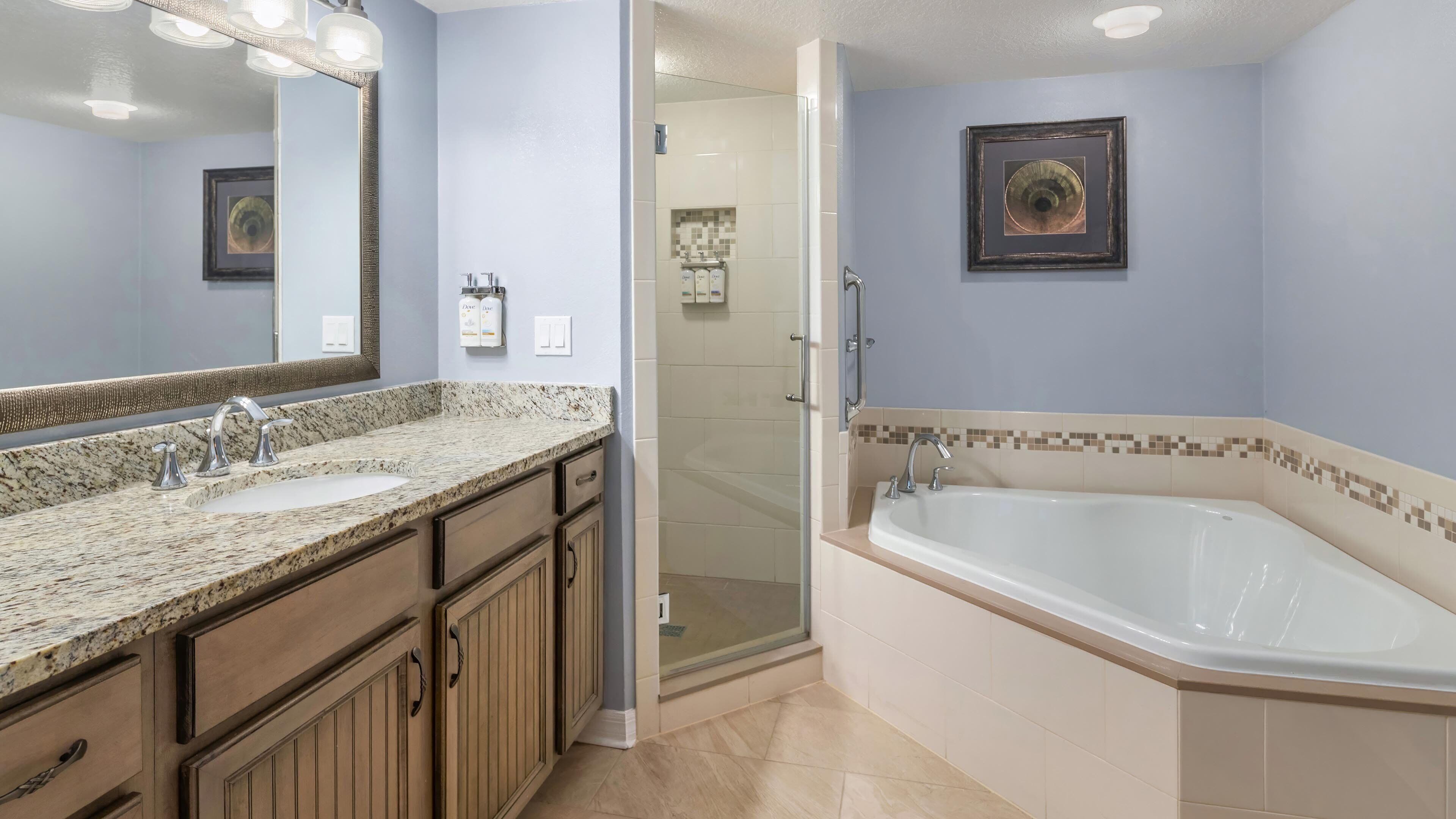 A bathroom with a double sink, a walk-in shower, and a large bathtub.
