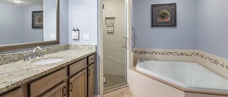 A bathroom with a double sink, a walk-in shower, and a large bathtub.