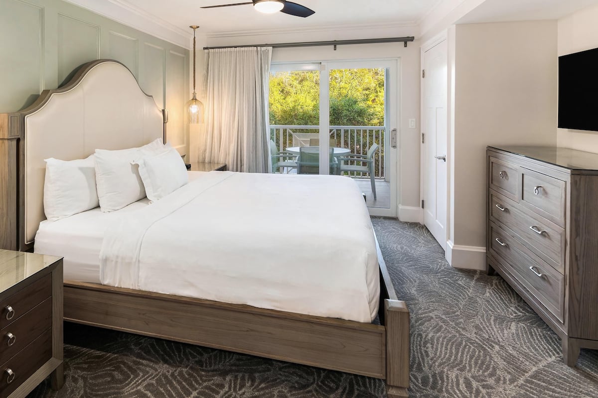 Ein Hotelzimmer mit Bett, Schminktisch, Fernseher und einem Balkon mit Blick.