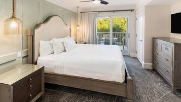 Une chambre d’hôtel avec un lit, une commode, une télévision et un balcon offrant une vue.