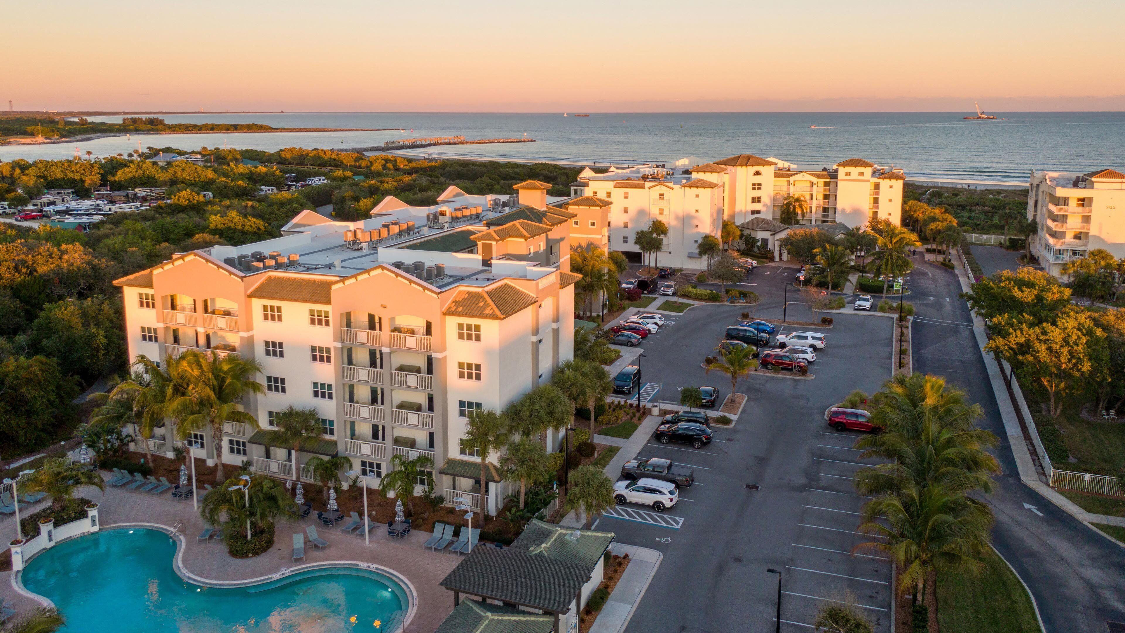 A resort with a swimming pool, multiple-story buildings, and a parking lot.
