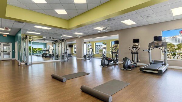 Un gimnasio con equipo de ejercicio, un espejo y vistas al exterior.