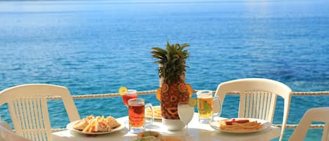 Una mesa con comida y bebidas, con vista a un cuerpo de agua.