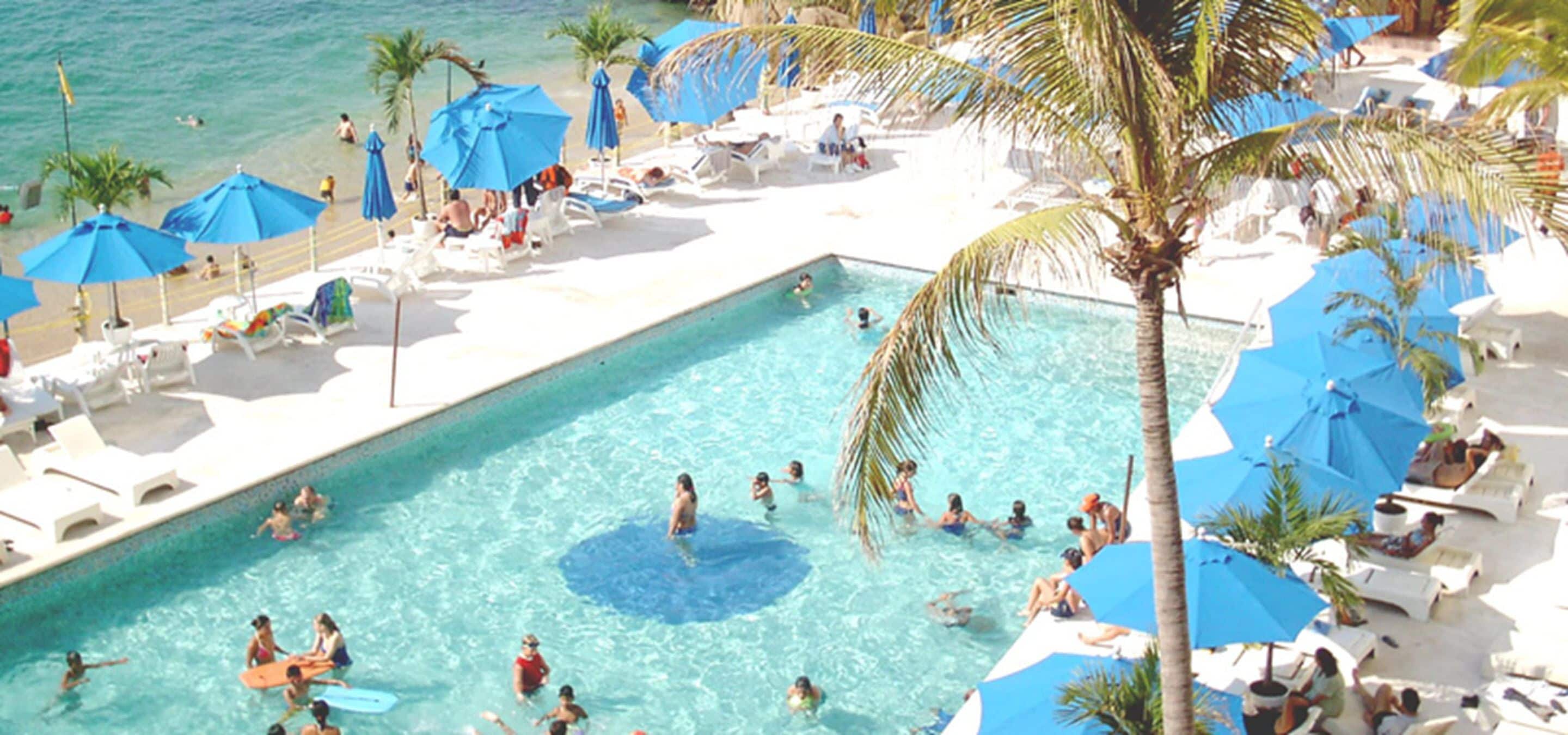 A pool area with lounge chairs and umbrellas, surrounded by palm trees.