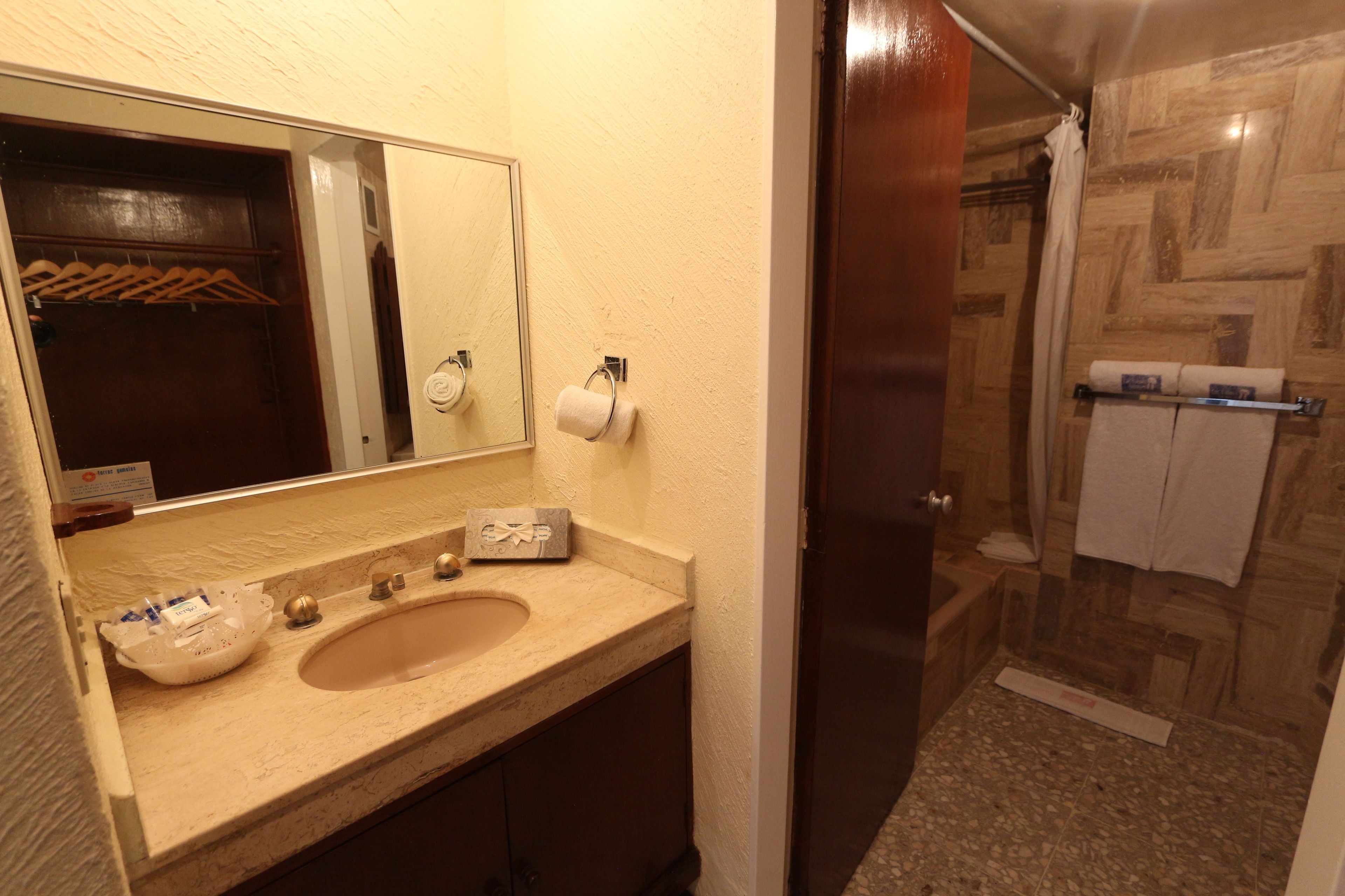 A bathroom with a double sink, a mirror, a towel rack, and a shower area.