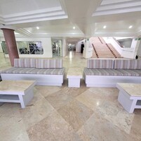 Um hall amplo com área de estar central, escada e parede de vidro.