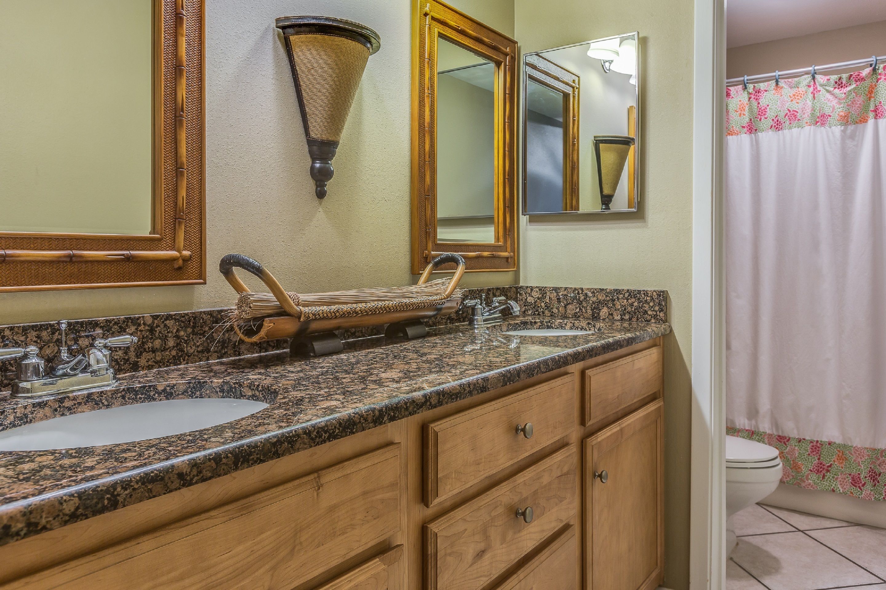 A bathroom with two sinks, wooden cabinets, a large mirror, and a shower curtain.