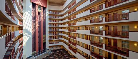 A multi-level hotel interior with a central atrium, balconies, and a dining area.