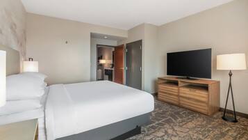 Una habitación de hotel con una cama, televisión, escritorio y lámpara.