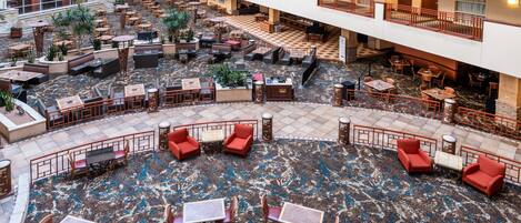 A multi-level hotel lobby with outdoor seating, a fountain, and a checkered floor pattern.