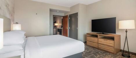 A hotel room with a bed, a television, a wooden dresser, and a lamp.