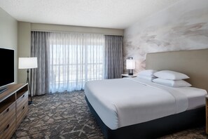 A hotel room with a large bed, a flat-screen TV, a desk, and a lamp. - Embassy Suites by Hilton Albuquerque (Albuquerque)