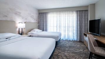 A hotel room with two beds, a television, a desk, and a chair.