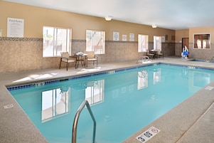 Área interna com piscina, regras da piscina afixadas, espaço de estar com cadeiras e cadeira do salva-vidas.