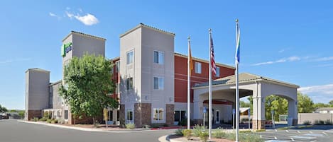 A hotel with a central courtyard, multiple flagpoles, and a clear blue sky.