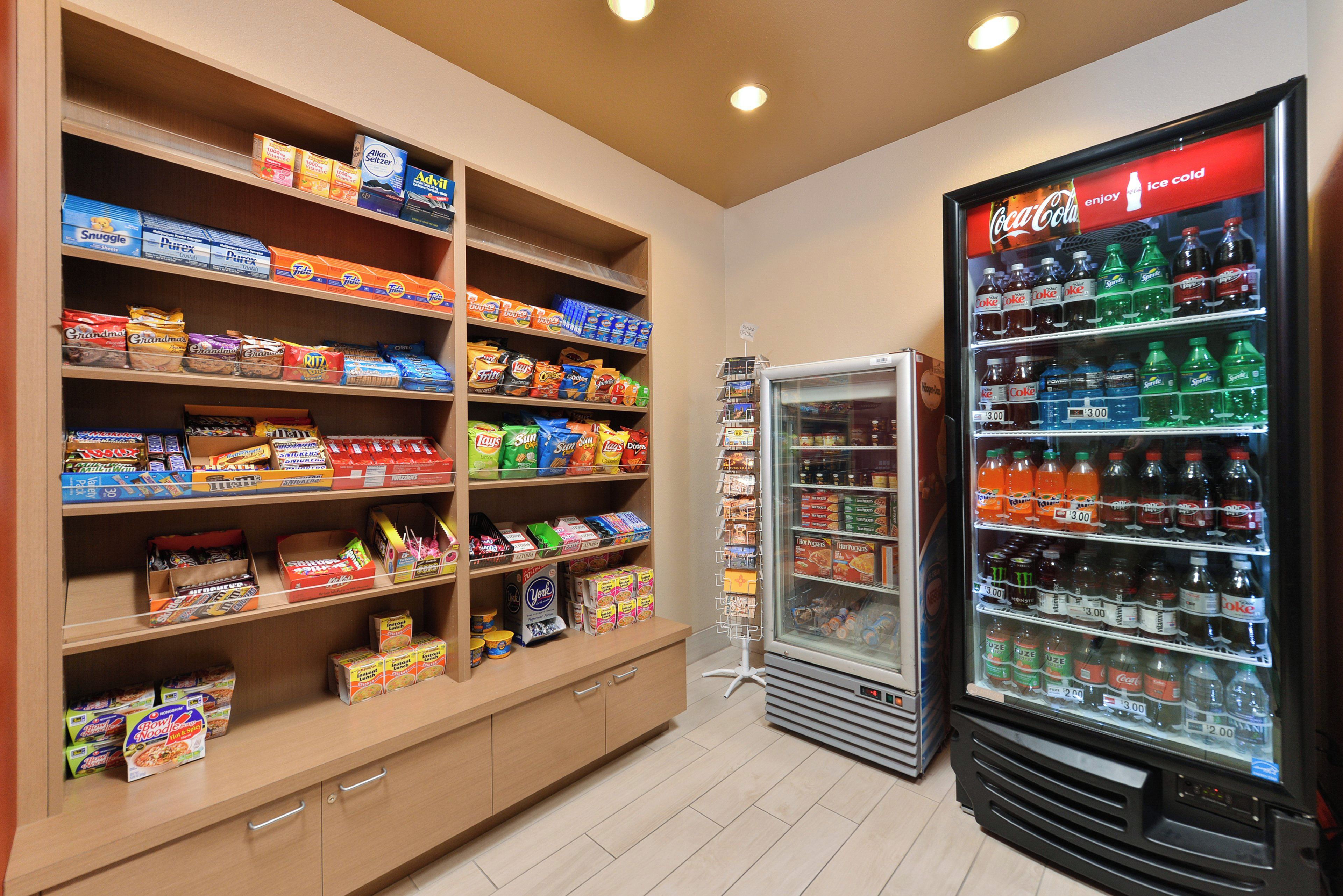 A snack and beverage area with shelves stocked with various snacks and a refrigerator with multiple beverage options.
