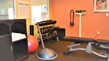A fitness center with exercise equipment, a bench, and a wall-mounted scale.