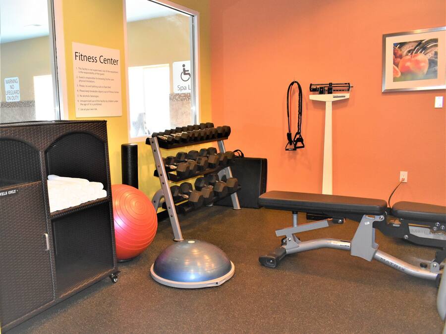 A fitness center with exercise equipment, a bench, and a wall-mounted scale.