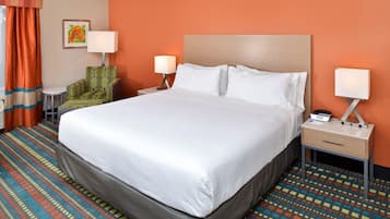 A hotel room with a large bed, two bedside tables, a chair, and a patterned carpet.