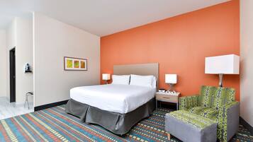 A hotel room with a bed, a chair, a nightstand, and a lamp.