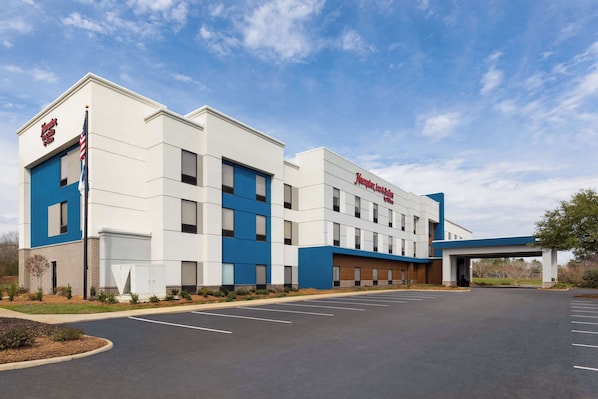 A modern hotel with a flat roof, a parking lot, and a clear sky. - Hampton Inn & Suites Dothan (Dothan)