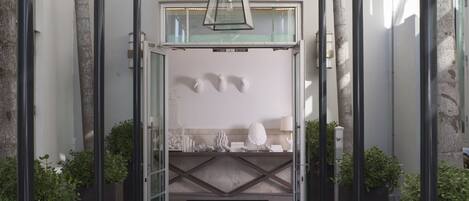 A hotel entrance with a modern design, featuring a glass door, a black doormat, and a geometric ceiling structure.