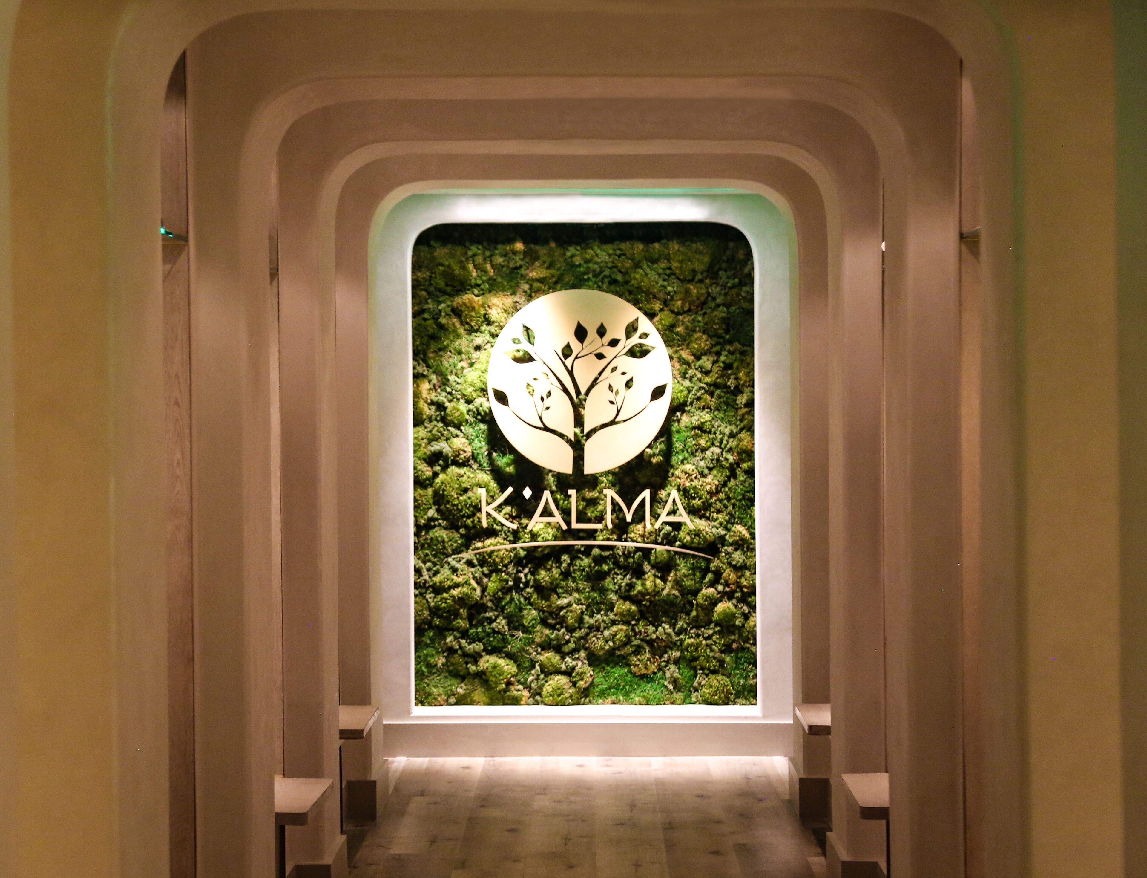 A hallway with a wall-mounted sign displaying the logo and name 'K'ALMA'.