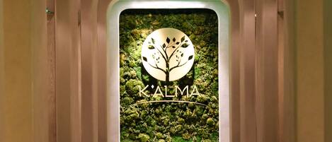 A hallway with a wall-mounted sign displaying the logo and name 'K'ALMA'.