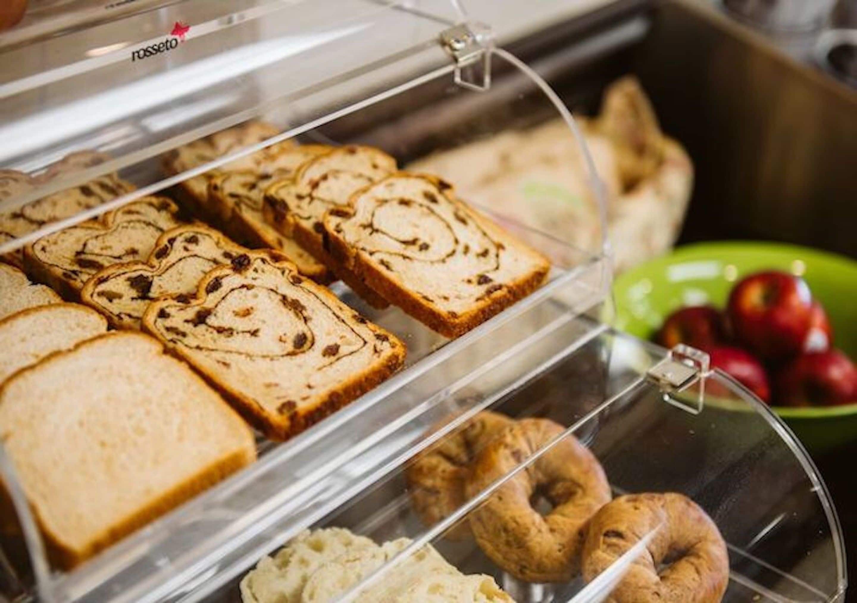 A display case with various pastries, including bread and donuts.