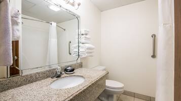 A bathroom with a granite countertop sink, a mirror, a toilet, and a shower curtain.