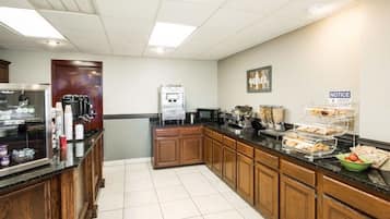 A hotel kitchen with a coffee station, a refrigerator, and a notice board.