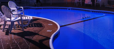 Une zone avec une piscine, des chaises et un bâtiment en arrière-plan.