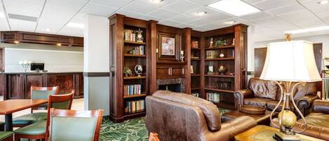Een bibliotheek met leren banken, houten boekenkasten en een eethoek met een groen tapijt.