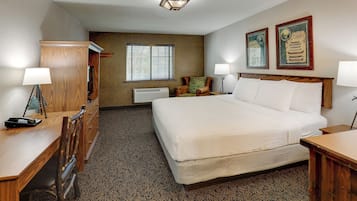 Een hotelkamer met een groot bed, een houten bureau, een stoel, een kastje en twee wandlampen.