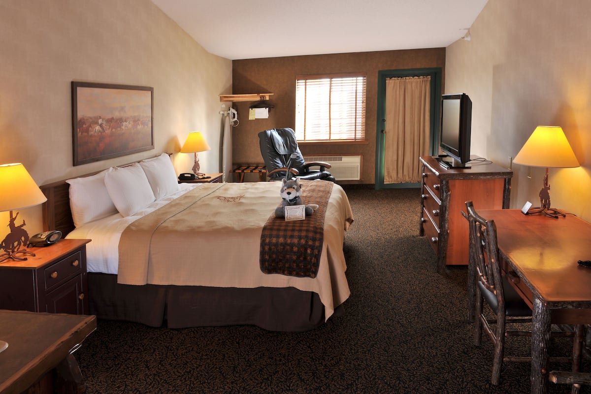 Une chambre d’hôtel avec un grand lit, un bureau, une chaise, une télévision et une fenêtre avec des rideaux.
