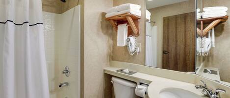 A bathroom with a shower, toilet, sink, and towel rack.