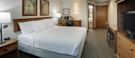 Habitación de hotel con una cama grande, un escritorio con lámpara, microondas y televisión.