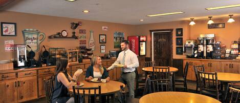 A restaurant with wooden tables and chairs, a coffee machine, and various wall decorations.