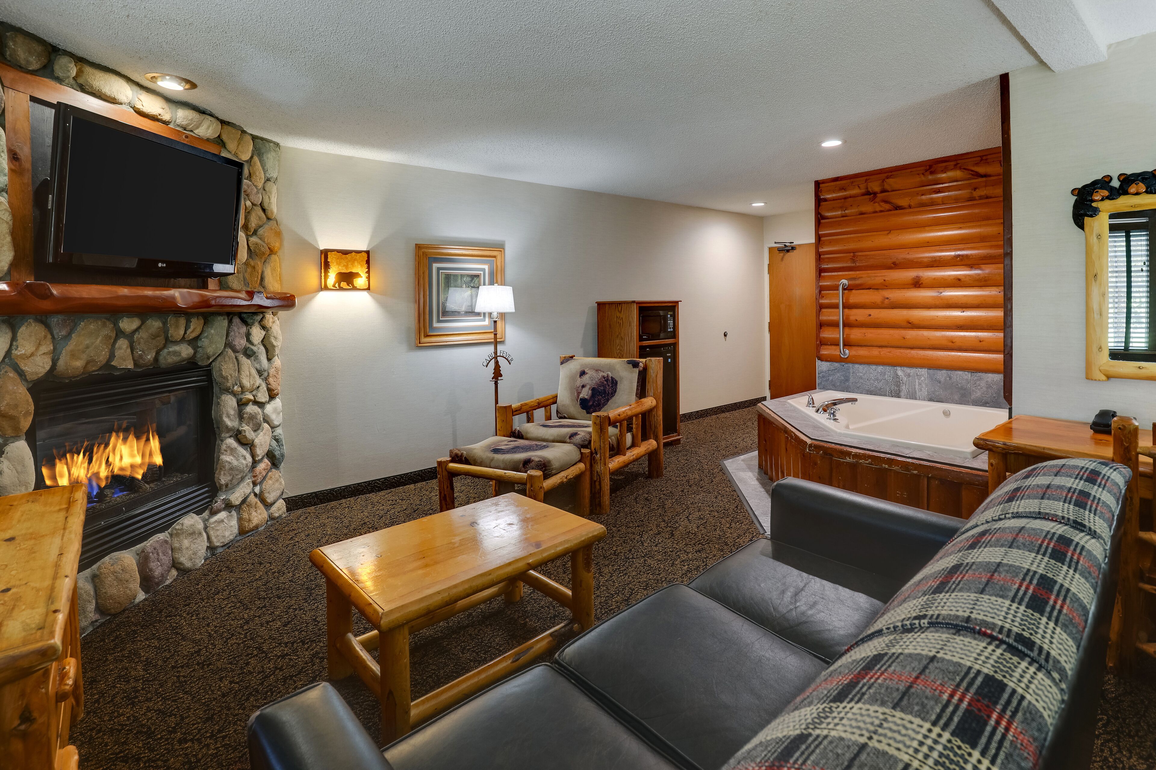 A cozy living room with a stone fireplace, a flat-screen TV, a wooden bench, a sofa, and a small table.
