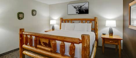 Una cama de madera con cabecera, dos mesitas de noche con lámparas y un cuadro enmarcado en la pared.