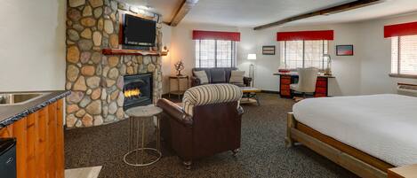 A cozy room with a stone fireplace, a bed, a sofa, and a desk with a computer.