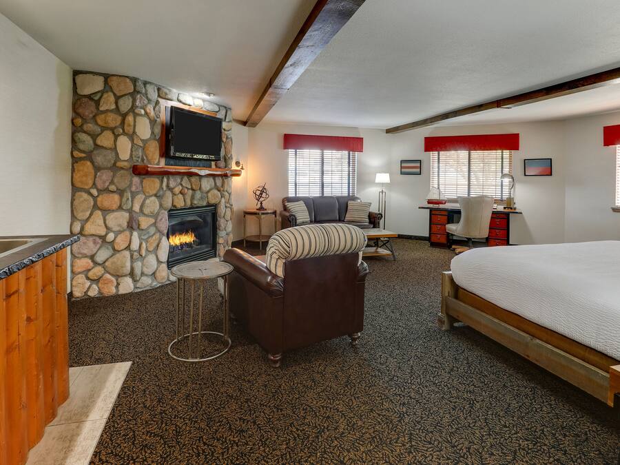 A cozy room with a stone fireplace, a bed, a sofa, and a desk with a computer.