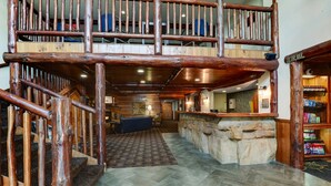 Eine geräumige Lobby mit einer Holztreppe, einer Bar und einer Steinwand.