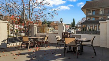 Un patio al aire libre con mesas y sillas, vistas a la calle y un edificio al fondo.